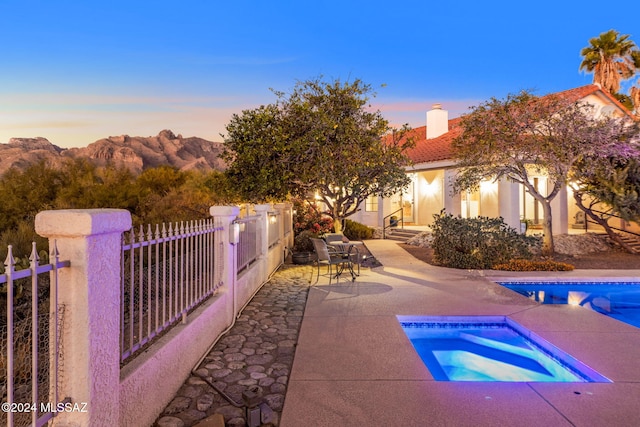 outdoor pool featuring an in ground hot tub, fence, a mountain view, and a patio area