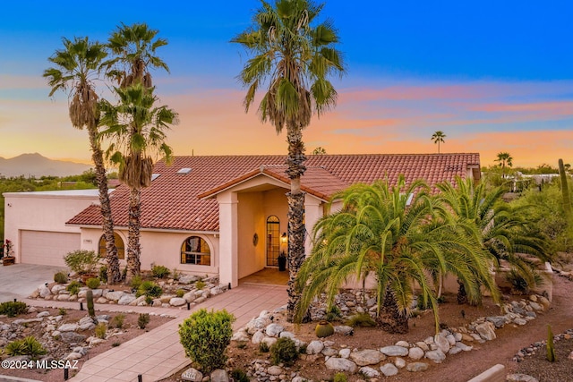 mediterranean / spanish-style house featuring stucco siding, concrete driveway, and a tiled roof