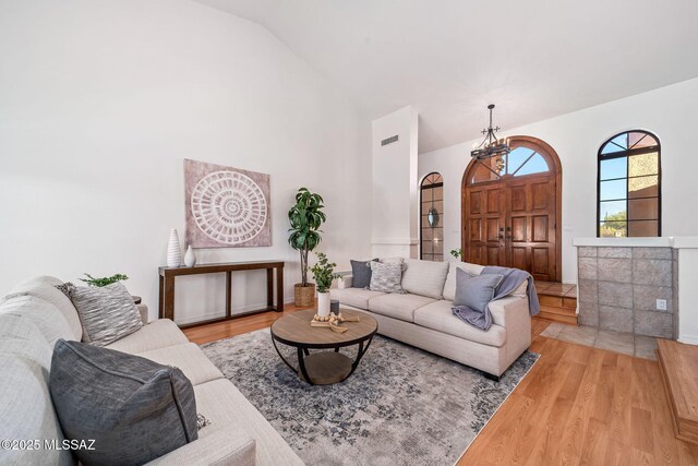 tiled living room with ceiling fan, a tiled fireplace, and high vaulted ceiling