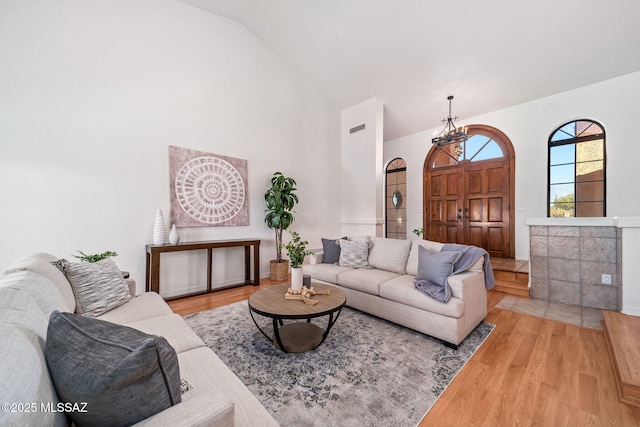 living area featuring visible vents, high vaulted ceiling, and wood finished floors