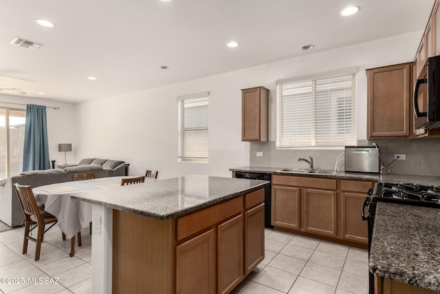 kitchen with backsplash, sink, a kitchen island, and black appliances