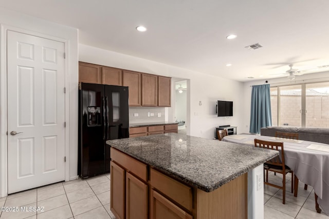 kitchen featuring black fridge with ice dispenser, a center island, ceiling fan, and light tile patterned flooring