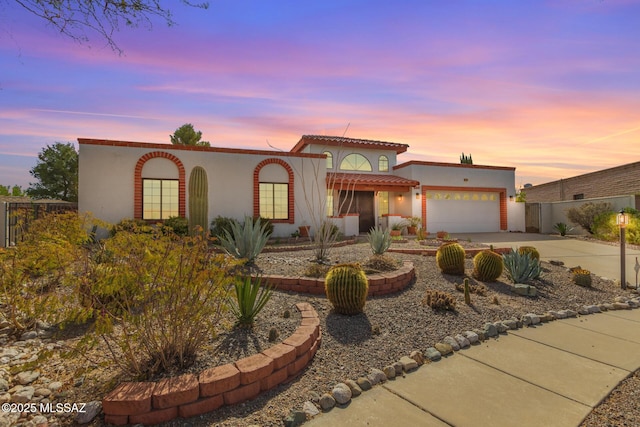 mediterranean / spanish house with fence, stucco siding, concrete driveway, a garage, and a tile roof