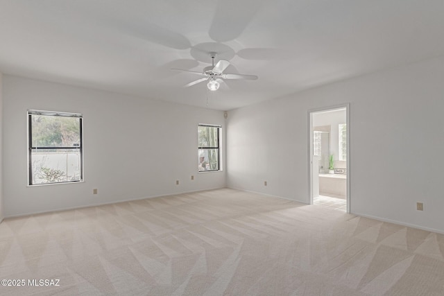 empty room with a ceiling fan, light colored carpet, and baseboards