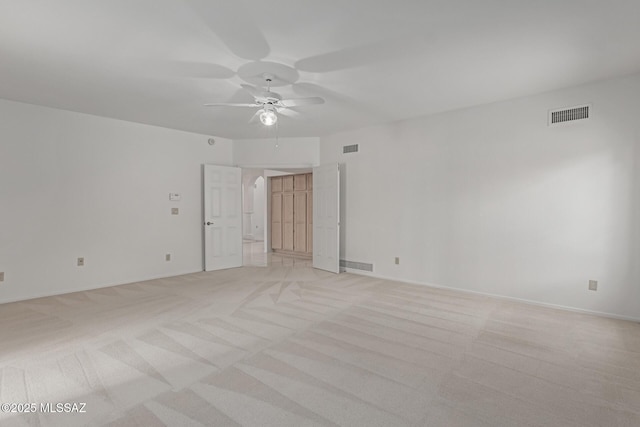 empty room featuring visible vents, light carpet, and ceiling fan