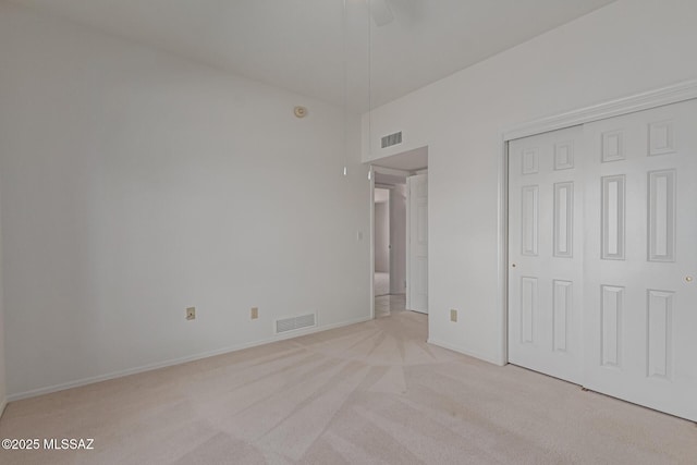 unfurnished bedroom featuring visible vents, baseboards, light colored carpet, and a closet