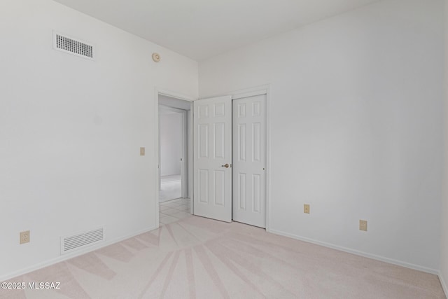 empty room featuring light carpet, visible vents, and baseboards