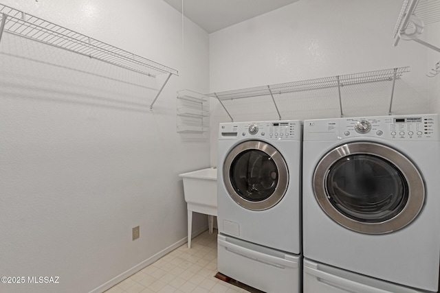 washroom featuring baseboards, washing machine and dryer, and laundry area