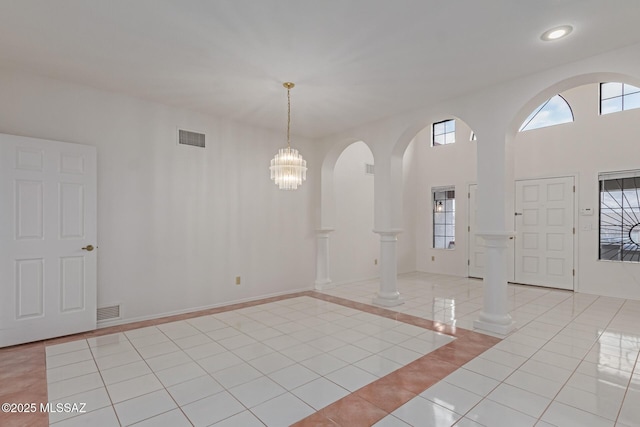 entrance foyer with light tile patterned flooring, visible vents, arched walkways, and baseboards