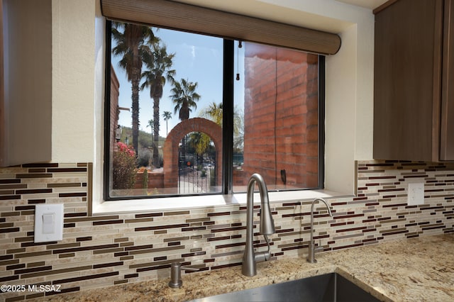 details featuring light stone countertops, sink, and backsplash