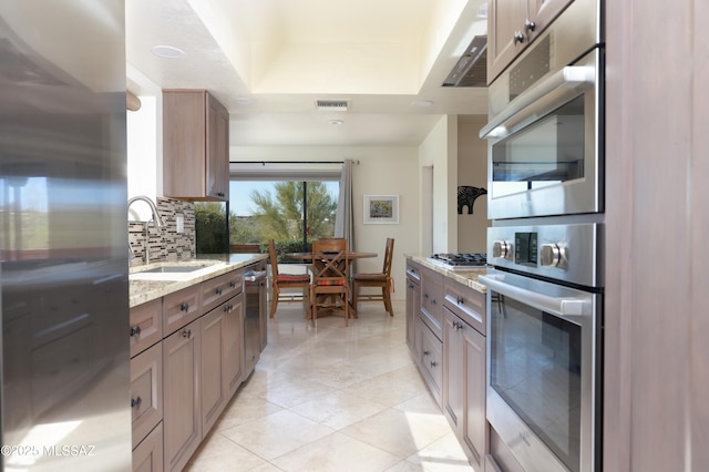 kitchen featuring sink, light tile patterned floors, stainless steel appliances, light stone countertops, and decorative backsplash