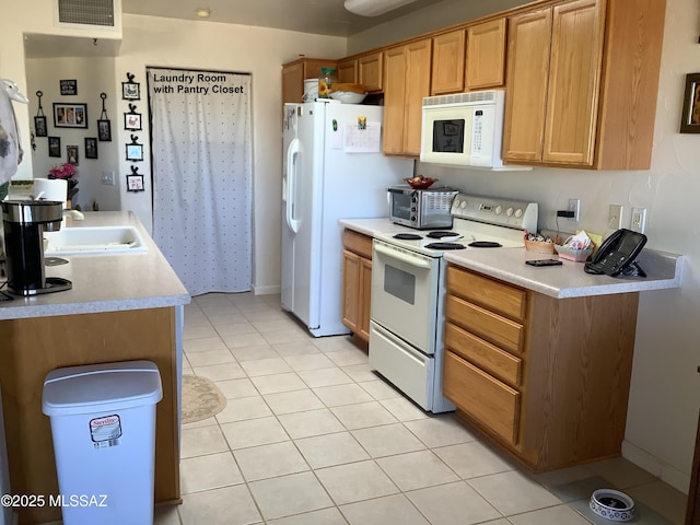 kitchen with light tile patterned flooring, white appliances, and sink