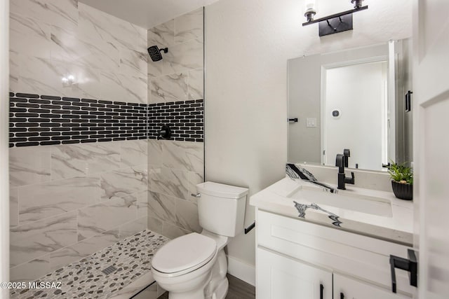 bathroom featuring vanity, tiled shower, and toilet