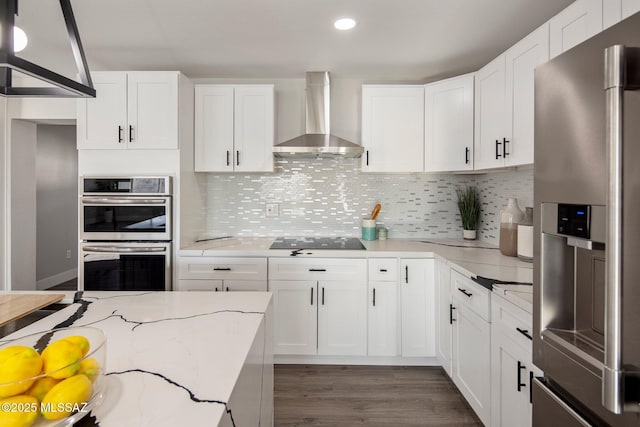 kitchen with wall chimney exhaust hood, white cabinetry, stainless steel appliances, and tasteful backsplash