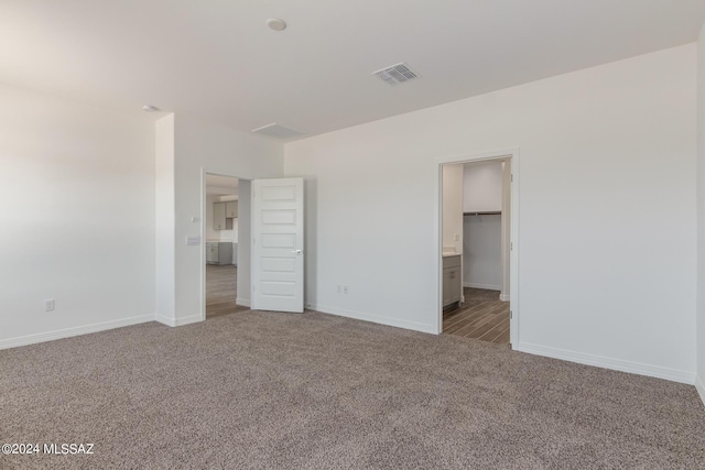 unfurnished bedroom featuring carpet, a spacious closet, connected bathroom, and a closet