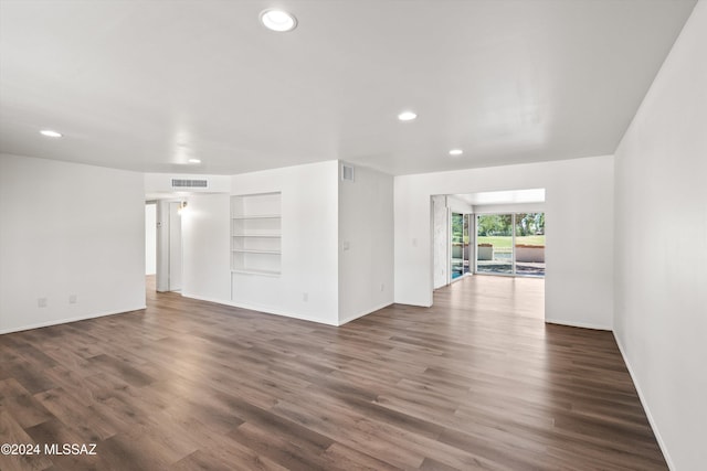 unfurnished room with baseboards, visible vents, dark wood-style flooring, built in shelves, and recessed lighting