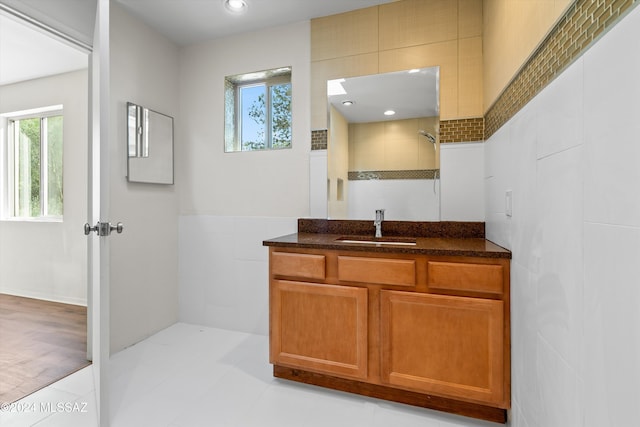 full bath with recessed lighting, a tile shower, vanity, and tile walls