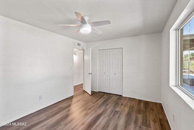 unfurnished bedroom featuring visible vents, baseboards, ceiling fan, dark wood-style flooring, and a closet