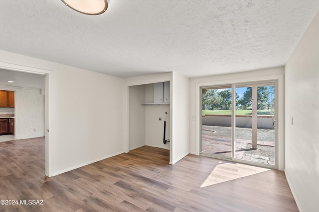 interior space with light wood finished floors, baseboards, and a textured ceiling