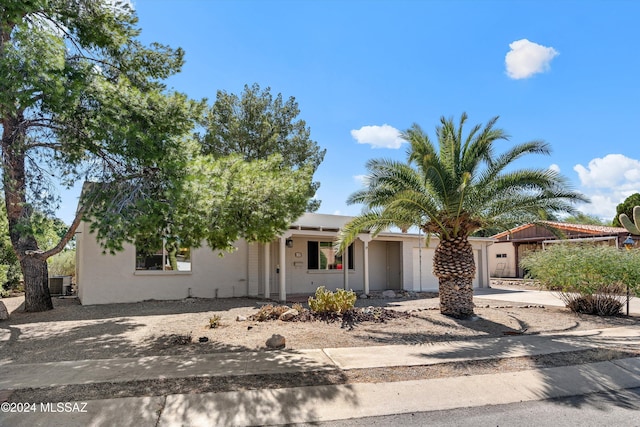 view of front of house featuring concrete driveway, central air condition unit, an attached garage, and stucco siding