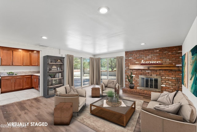 living area featuring visible vents, a brick fireplace, light wood-style flooring, and recessed lighting