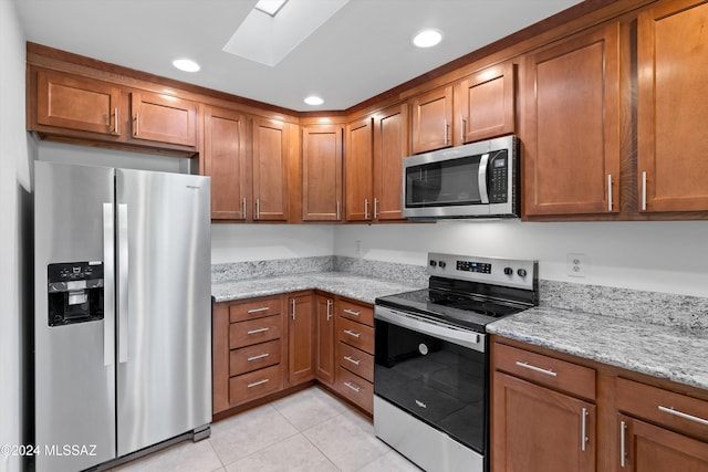 kitchen featuring appliances with stainless steel finishes, brown cabinetry, and light stone countertops