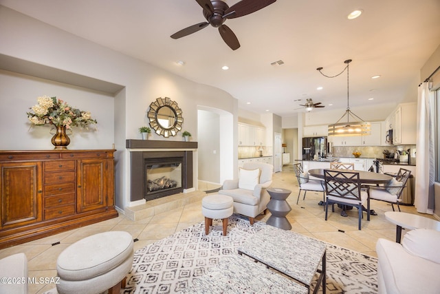 tiled living room featuring a tiled fireplace and ceiling fan