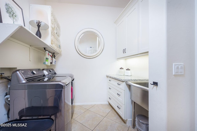 laundry room featuring separate washer and dryer, cabinets, and light tile patterned flooring