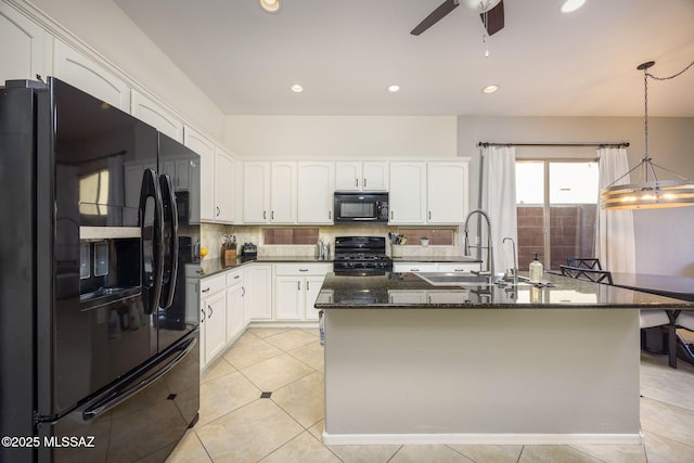 kitchen featuring sink, white cabinetry, hanging light fixtures, dark stone countertops, and black appliances