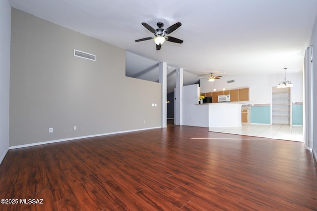 unfurnished living room featuring lofted ceiling, ceiling fan with notable chandelier, and light wood-type flooring