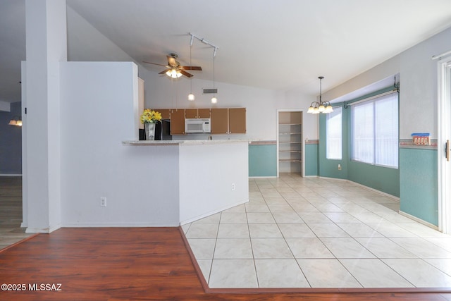 kitchen featuring light tile patterned flooring, ceiling fan with notable chandelier, lofted ceiling, fridge, and kitchen peninsula