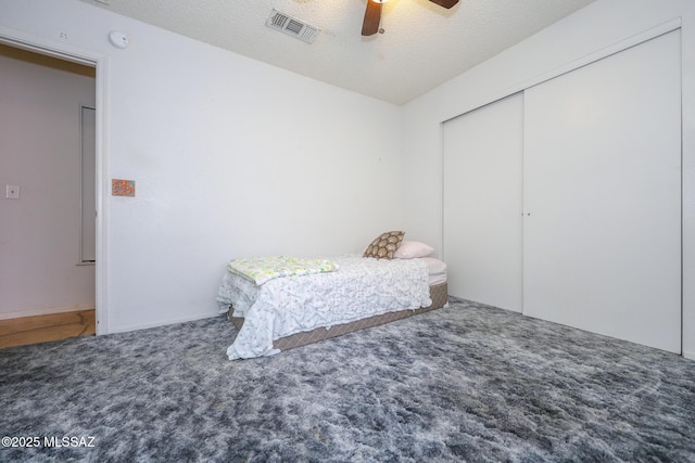 carpeted bedroom featuring ceiling fan, a closet, and a textured ceiling