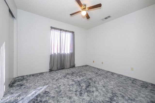 carpeted spare room featuring ceiling fan and a textured ceiling