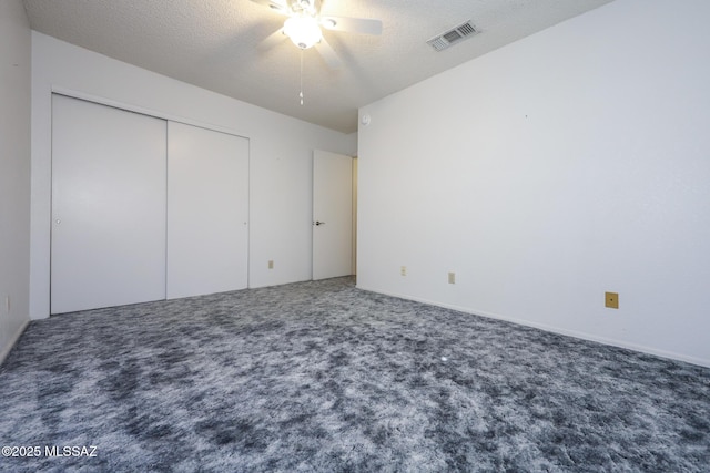 unfurnished bedroom featuring a textured ceiling, a closet, ceiling fan, and carpet