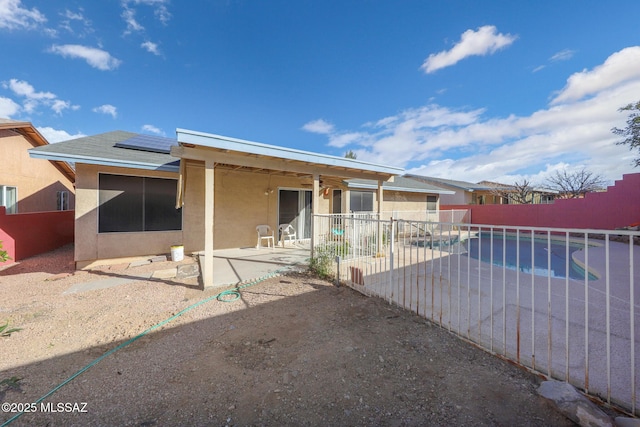 rear view of property featuring a patio and solar panels