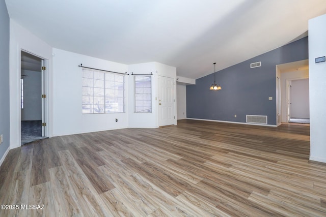 unfurnished living room with lofted ceiling, wood-type flooring, and a chandelier