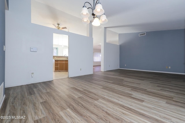 unfurnished living room featuring sink, ceiling fan with notable chandelier, vaulted ceiling, and wood-type flooring