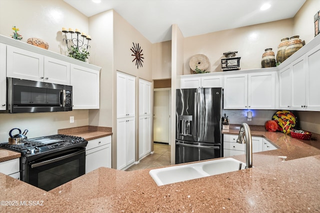 kitchen featuring light stone counters, white cabinets, sink, and black appliances