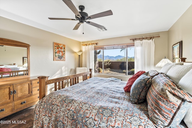 bedroom with a mountain view, dark hardwood / wood-style floors, and ceiling fan