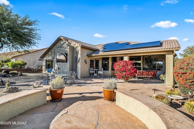 back of property featuring a patio area and solar panels