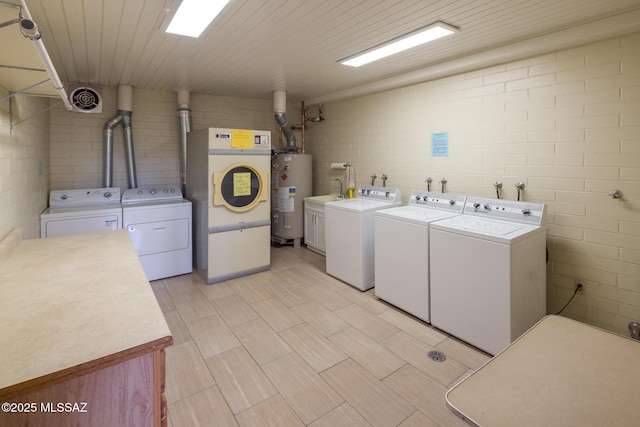 clothes washing area with washing machine and dryer and gas water heater