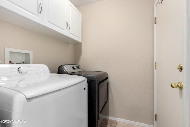 laundry room featuring cabinets, light tile patterned flooring, and washer and clothes dryer