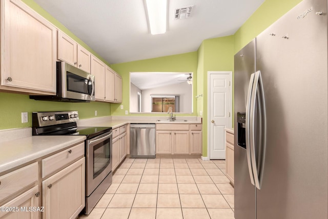 kitchen with sink, stainless steel appliances, light tile patterned flooring, vaulted ceiling, and light brown cabinets