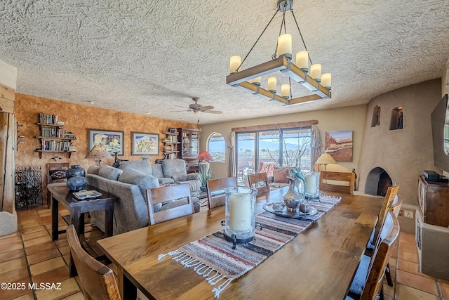 dining area featuring ceiling fan with notable chandelier and a textured ceiling