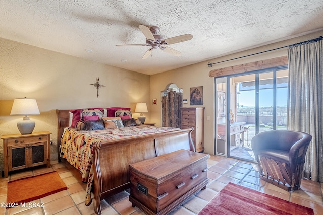 bedroom with ceiling fan, light tile patterned floors, a textured ceiling, and access to outside