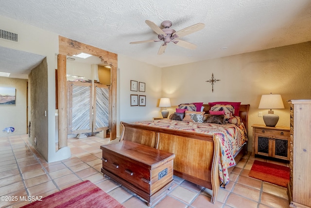 tiled bedroom with ceiling fan and a textured ceiling