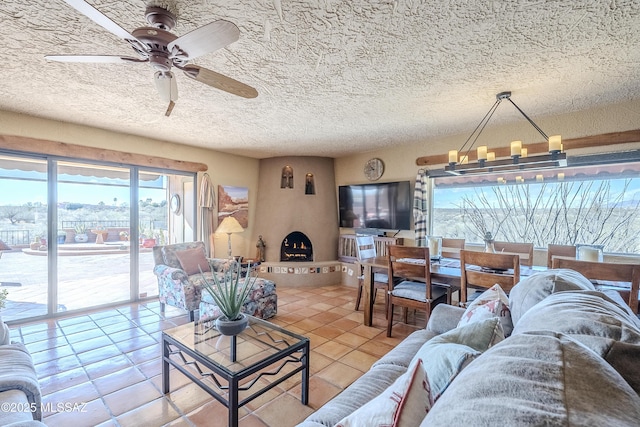 tiled living room with ceiling fan with notable chandelier, a large fireplace, and a textured ceiling