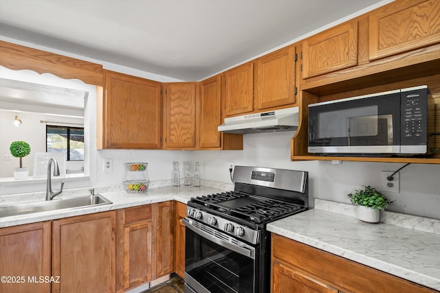 kitchen featuring sink, stainless steel gas range, and light stone countertops