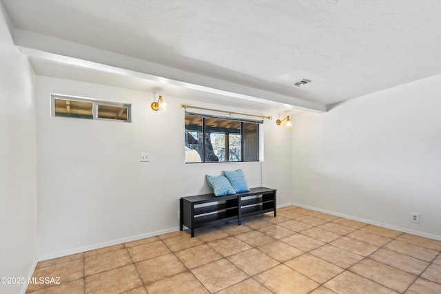 spare room featuring beamed ceiling and a textured ceiling