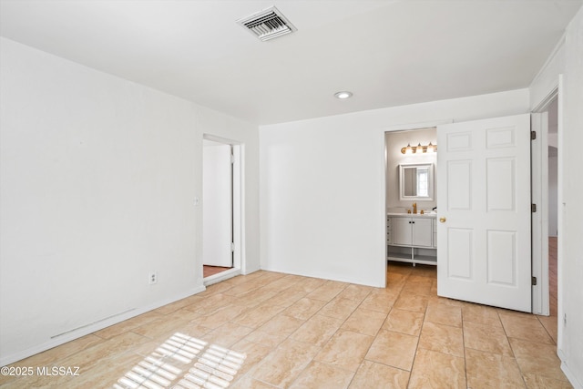 unfurnished bedroom with light tile patterned floors and ensuite bath